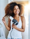 She knows how to care for curly hair. an attractive young woman drying her hair with a hairdryer at home. Royalty Free Stock Photo