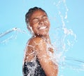 She knows how to have fun. a beautiful young woman being splashed with water against a blue background.