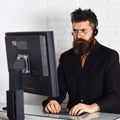 He knows how to help you. Call center operator at work. Man with long beard and headphones. Bearded man working in