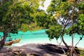 KO LIPE, THAILAND ANDAMAN SEA - DECEMBER 28. 2013: View beyond trees and rocky plateau on long tail boats and turquoise