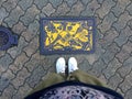 Female legs standing in front of a Yellow colored Manhole of Kobe City, Japan
