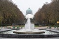 Koekelberg, Brussels Capital Region, Belgium - View over a city fountain, a colorful tree lane and the Basilica of the