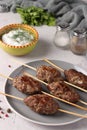 Kofta kebab on wooden skewers on a plate and sauce on the table, traditional dish of Arab cuisine, grilled minced meat shish kebab Royalty Free Stock Photo