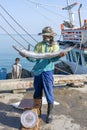 Thai fisherman shows caught fish on the pier near fishing boat on the island Koh Phangan, Thailand Royalty Free Stock Photo