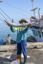 Thai fisherman shows caught fish on the pier near fishing boat on the island Koh Phangan, Thailand