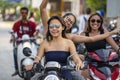 A young woman with happy girl riding a motorcycle on road. Asian girls rides scooter in the city street at island Koh Phangan,