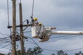 Two male electrician officer standing in mobile crane bucket and repairs a wire of the power electrical line, Thailand