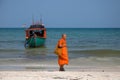 Koh Rong island, Cambodia - 07 April 2018: Buddhist monk in orange clothes on white sand beach.