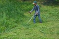 Gardener cutting grass using gasoline brush cutter