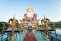 KOH SAMUI, THAILAND - January 10, 2020: Man with a camera stands on a bridge to a giant colorful buddha statue at wat