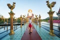 KOH SAMUI, THAILAND - January 10, 2020: Woman in a red dress standing on a bridge to a giant colorful buddha statue at