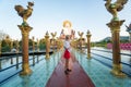 KOH SAMUI, THAILAND - January 10, 2020: Woman in a red dress standing on a bridge to a giant colorful buddha statue at