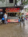 A street breakfast center or street food stall at the corner of busy Indian market street. Hotel with red name board and chef