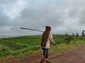 an Old Indian man wearing casual cloths and jute sack as raincoat walking on road. Royalty Free Stock Photo