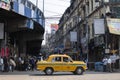 Kolkata, India - February 1, 2020: Unidentified people stands and walks on the street as a traditional yellow taxi drives by Royalty Free Stock Photo