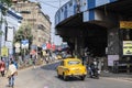 Kolkata, India - February 1, 2020: Unidentified people stands and walks on the street as a traditional yellow taxi drives by Royalty Free Stock Photo