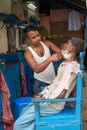 Indian barber shaving man on the street in Kolkata. India