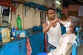 Indian barber shaving man on the street in Kolkata. India
