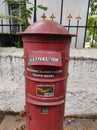 Red colored post box placed on the street operated by the Indian postal office and mail service.