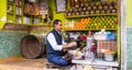 An Indian man peeling fruits in his colorful juice shop on the streets of the city of