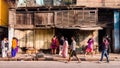 People walking past a rustic wooden shop house on the streets of the Kumartuli area of