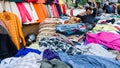 A street vendor sitting on a pile of clothes at his roadside textile store in the city