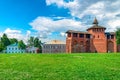 Kolomna kremlin red brick wall adn old houses along green grass. Brickwork wall of the Kolomna Kremlin against blue dramatic cloud