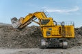 Komatsu PC4000 excavator with lifted bucket filled with ore in an open pit.