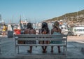 Komiza, Croatia - Aug 16, 2020: Tourists sit on bench in front of old town port Royalty Free Stock Photo