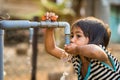 Kon Tum, Vietnam - Mar 29, 2016: A little girl drink water from outdoor tap which water supplied by drilling well in Central Highl