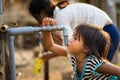 Kon Tum, Vietnam - Mar 29, 2016: A little girl drink water from outdoor tap which water supplied by drilling well in Central Highl