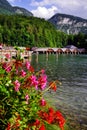 Flowers, pier and wooden boat houses on the shore of Konigssee Lake.