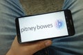 Man holding smartphone with Pitney Bowes company logo