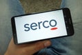Man holding smartphone with Serco Group plc logo