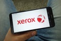 Man holding smartphone with Xerox Corporation logo