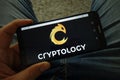 Man holding smartphone with Cryptology cryptocurrency exchange logo