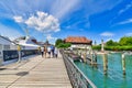 Konstanz, Germany - July 2020: Long wooden footbridge at Lake Constance harbor with tourists and anchored cruise ship Royalty Free Stock Photo