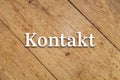 `Kontakt` white text on a wooden background. Translation: Contact