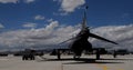 Military jet fighter plane parked at an airbase for refueling viewed from behind