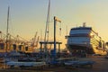 View of moored huge luxury cruise ship during sunrise. Port for yachts in the foreground