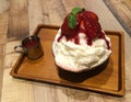 Korea shaved ice, strawberry bingsu top with little mint leaf on the wood table server with strawberry sauce