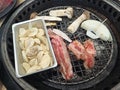 Korean Barbecue consist of beef, garlic, onion, and shimeji mushroom on a charcoal grill