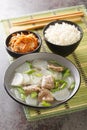 Korean Beef Radish Soup Sogogi Muguk served with rice and kimchi closeup on the mat. Vertical