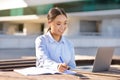 Korean business lady near laptop browsing and writing, sitting outdoors Royalty Free Stock Photo