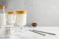 Korean Dalgona coffee in tall glass mugs. Trendy refreshment creamy whipped iced coffee. Light gray concrete background.