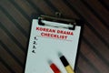 Korean Drama Checklist write on a paperwork and supported by additional services isolated on Wooden Table