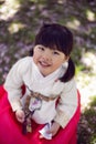 Korean girl child in a national costume walks in a garden with cherry blossoms in spring.