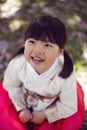 Korean girl child in a national costume walks in a garden with cherry blossoms in spring.