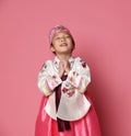 Korean little baby girl in traditional silk dress for new year celebration on pink with hands in pray sign