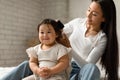 Korean Mom Brushing And Detangling Baby Daughter's Hair In Bedroom Royalty Free Stock Photo